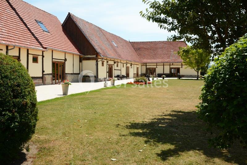Location salle Argueil (Seine-Maritime) - Domaine de Clairval #5 Bâtiments à toit en tuiles rouges entourés d'une cour en pelouse et d'arbres sous un ciel dégagé.