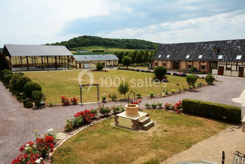 Location salle Argueil (Seine-Maritime) - Domaine de Clairval #4 Cour intérieure d'une propriété rurale avec pelouse, parterres de fleurs, bâtiments en pierre et structures agricoles.