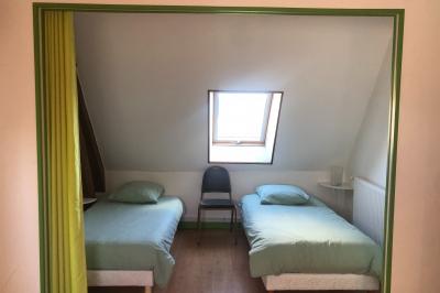 Miniature Box Lit double avec tête de lit sombre, draps gris et blancs, encadré par deux tables de chevet avec lampes, dans une chambre…