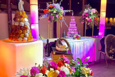 Miniature Cérémonie du dessert - sous la Halle Table garnie de pâtisseries, macarons, fruits et biscuits, disposée en extérieur avec un jardin en arrière-plan.