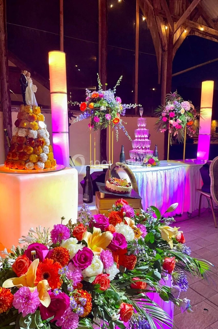 Cérémonie du dessert - sous la Halle Table décorée pour une réception avec fleurs colorées, pièce montée, fontaine de champagne et éclairage chaleureux.