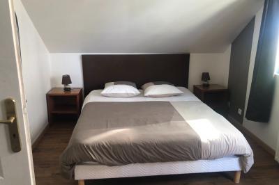 Miniature Chambre marron Lit double avec tête de lit sombre, draps gris et blancs, encadré par deux tables de chevet avec lampes, dans une chambre…