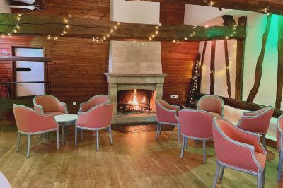 Miniature Cheminée Grande Clairval Lit double avec tête de lit sombre, draps gris et blancs, encadré par deux tables de chevet avec lampes, dans une chambre…