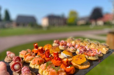 Miniature Cocktail - Extérieur Table garnie de pâtisseries, macarons, fruits et biscuits, disposée en extérieur avec un jardin en arrière-plan.