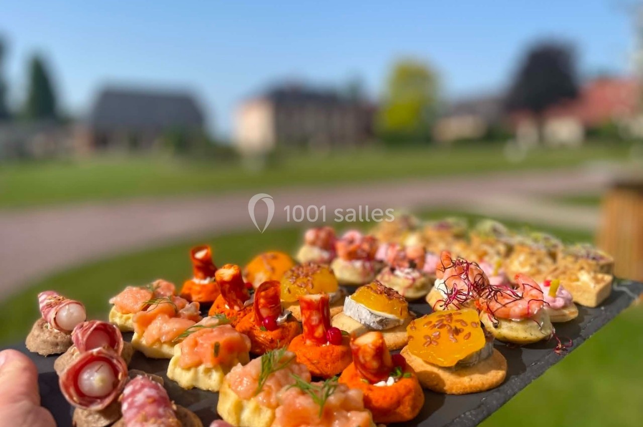 Cocktail - Extérieur Plateau d'amuse-bouches variés présenté en extérieur, avec un jardin flou en arrière-plan.
