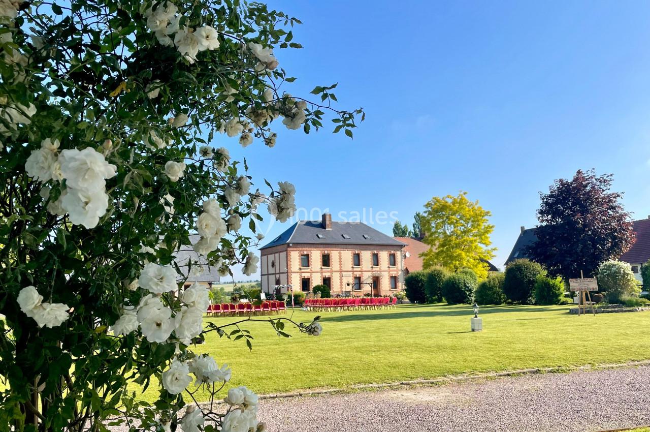 Jardin Vue d'une maison en briques entourée d'un jardin verdoyant, avec des fleurs blanches au premier plan.