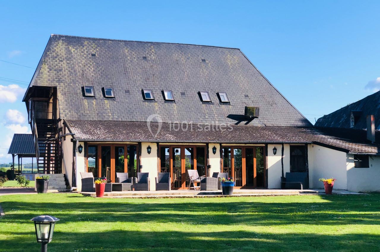 La Charretterie - Extérieur (terrasse) Grande maison avec toit en ardoise, nombreuses fenêtres et terrasse aménagée, entourée d'une pelouse verte.