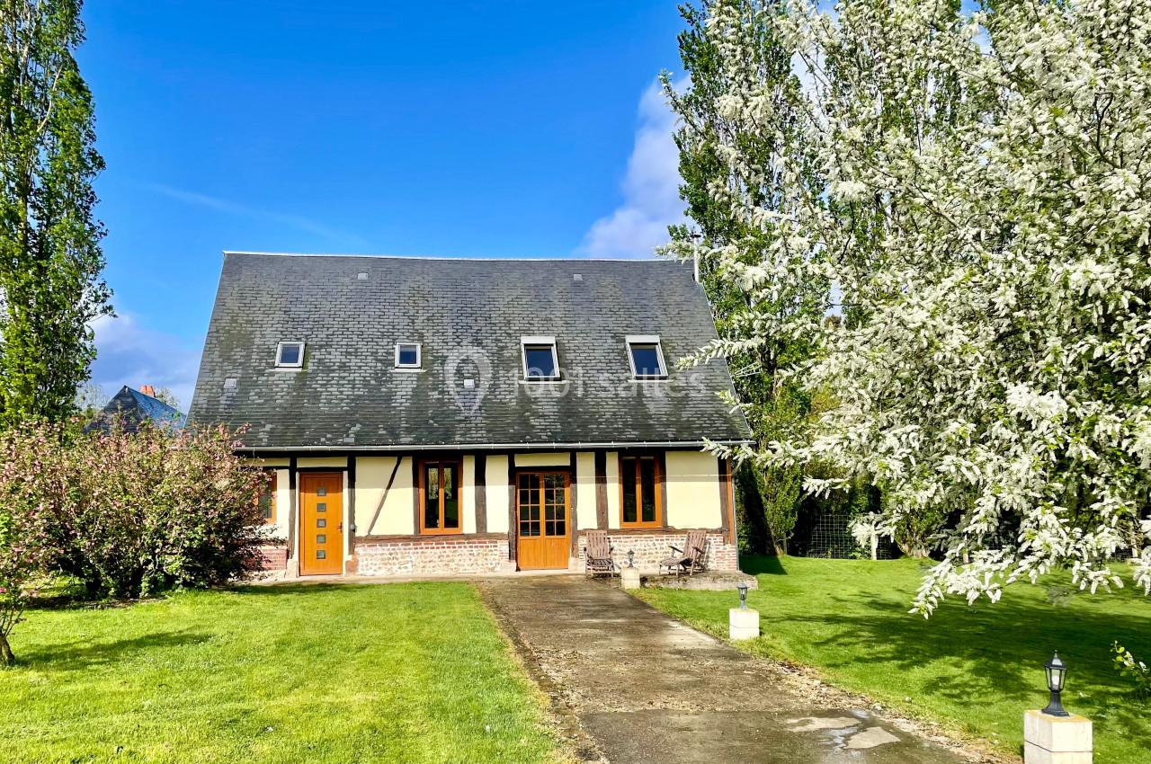 La Petite maison dans la prairie (Bâtiment pour les mariés) Maison à colombages entourée d'arbres en fleurs et d'une pelouse, avec une allée pavée menant à l'entrée.