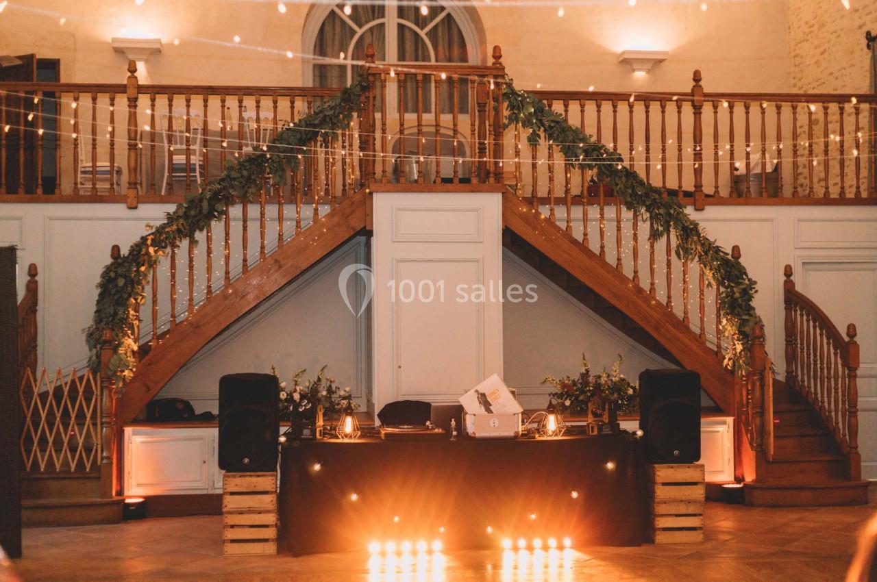 Escalier en bois décoré de guirlandes lumineuses et de verdure, avec une table de DJ éclairée au premier plan.