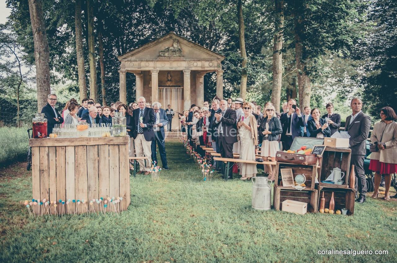 Groupe de personnes rassemblées dans un jardin devant un kiosque en pierre, avec un buffet en bois au premier plan.