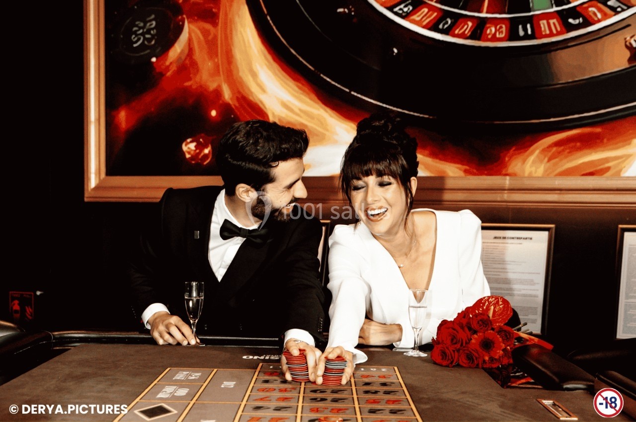 Un homme et une femme élégamment vêtus jouent à la roulette dans un casino, souriant et échangeant des jetons.