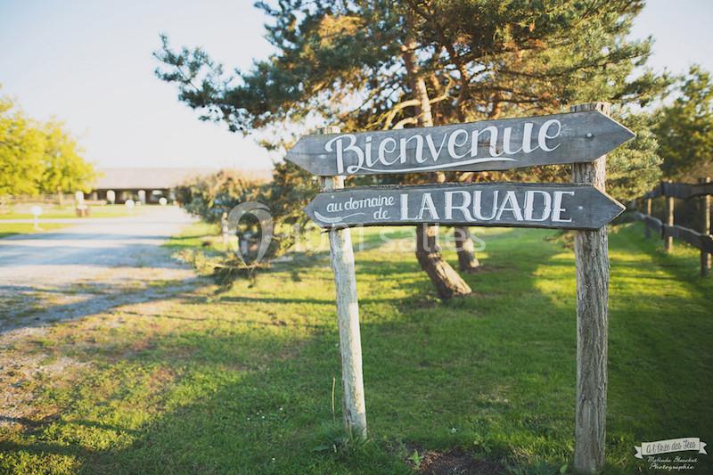 Panneaux en bois indiquant ’Bienvenue au domaine de la Ruarade’ dans un cadre verdoyant avec arbres et pelouse.