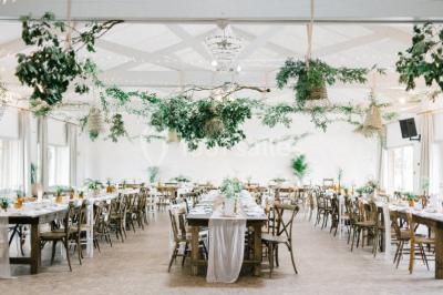 Vue d'une grange en bois entourée d'arbres, avec des bancs disposés en extérieur sur une pelouse.