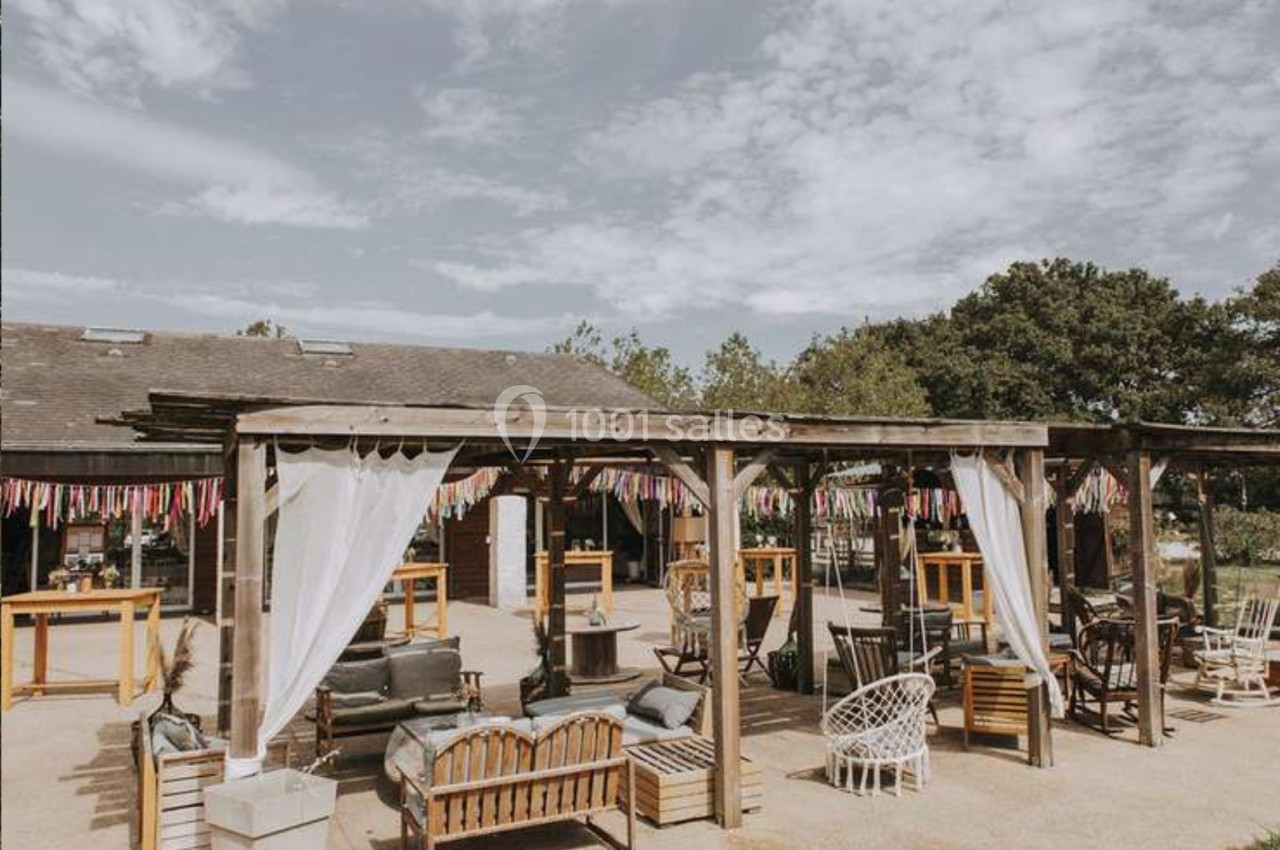Espace extérieur avec pergolas en bois, mobilier de jardin et décorations colorées sous un ciel partiellement nuageux.