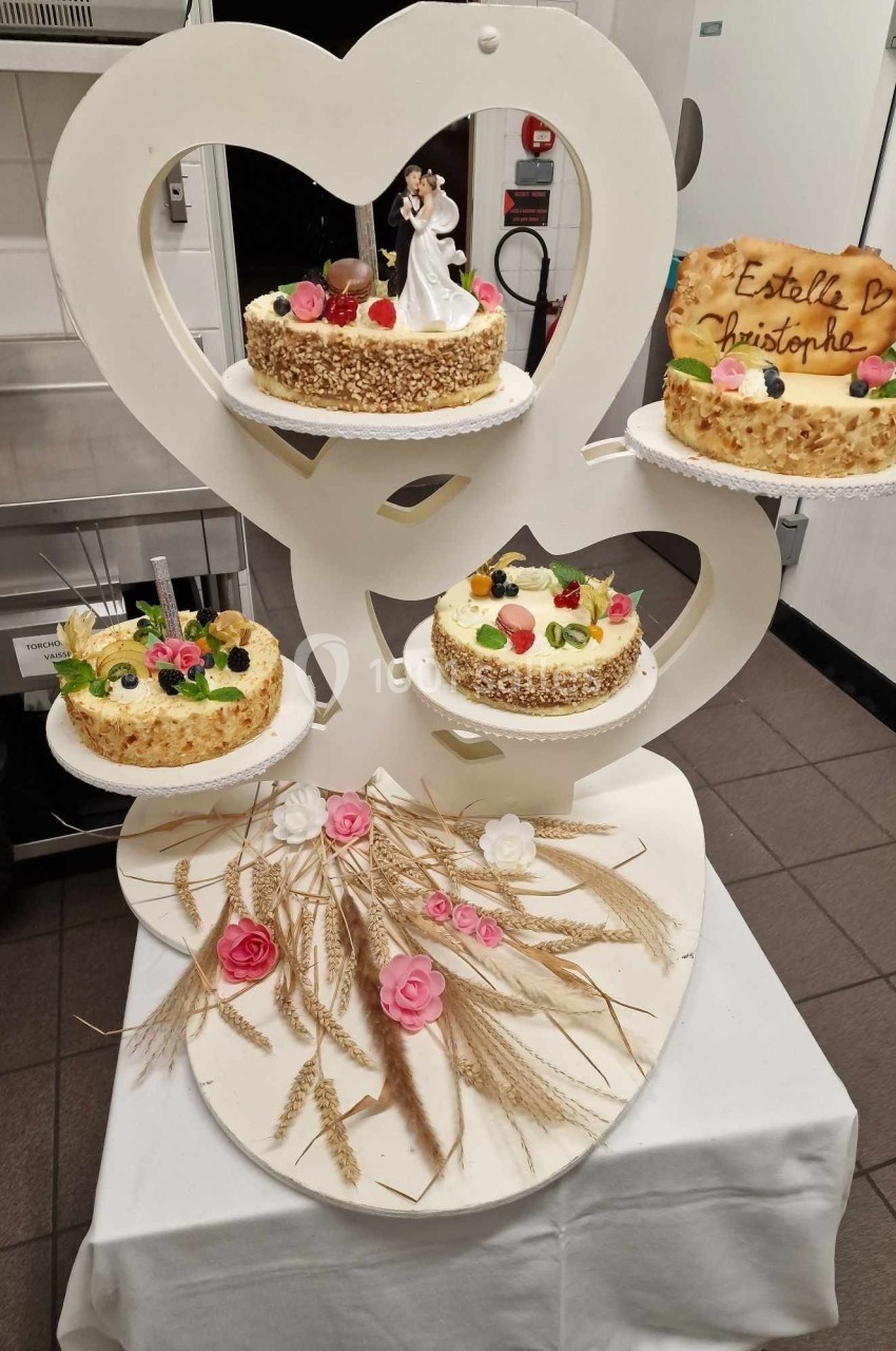 Location salle Les Villages Vovéens (Eure-et-Loir) - Hôtel Restaurant le Quai Fleuri #6 Présentoir en forme de cœur avec quatre gâteaux décorés de fruits et fleurs, accompagné d'épis de blé et roses.