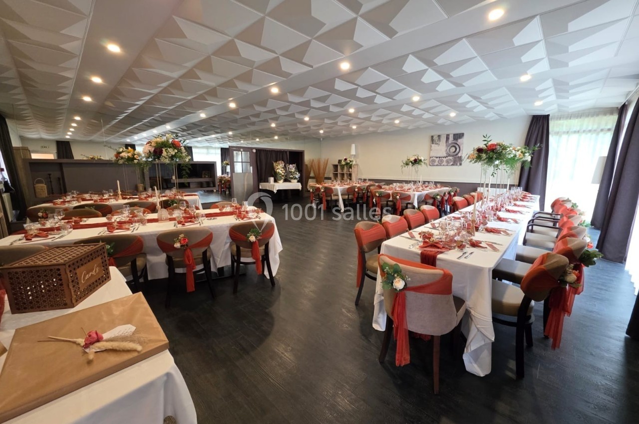Location salle Les Villages Vovéens (Eure-et-Loir) - Hôtel Restaurant le Quai Fleuri #20 Salle de réception décorée avec des tables dressées, chaises ornées de rubans rouges et arrangements floraux.