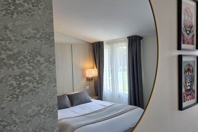 Salle de restaurant lumineuse avec tables dressées, chaises en bois sombre, étagères décoratives et plantes vertes.