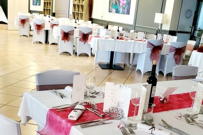 Salle de restaurant lumineuse avec tables dressées, chaises en bois sombre, étagères décoratives et plantes vertes.