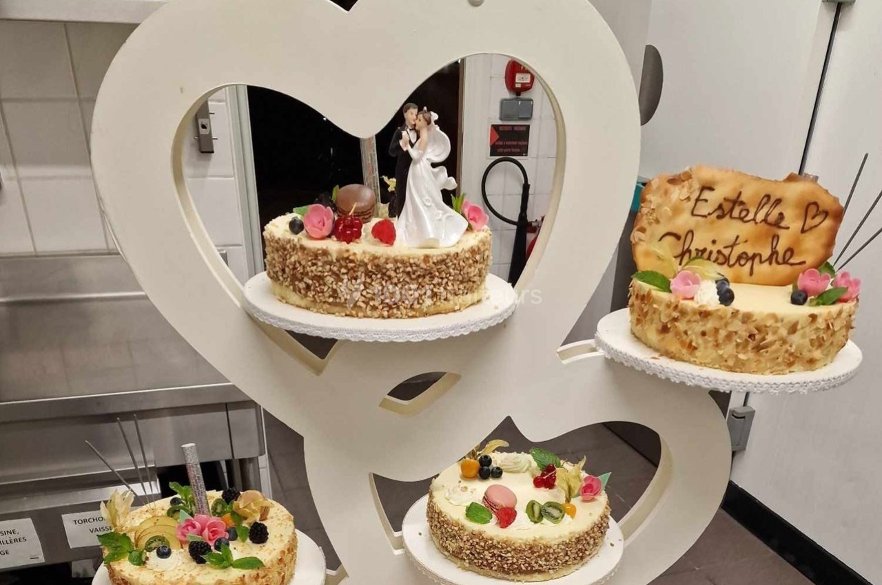 Quatre gâteaux décorés, dont un avec figurines de mariage et un autre portant les prénoms ’Estelle’ et ’Christophe’.