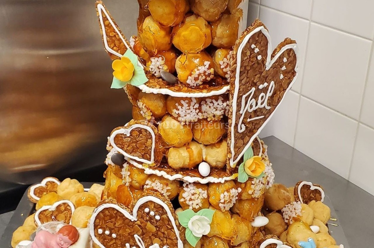 Pièce montée en choux décorée de cœurs en nougatine, fleurs en sucre et figurines pour une célébration.