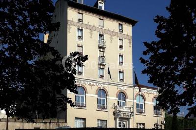 Façade d'un hôtel ancien à plusieurs étages, avec des fenêtres symétriques et un ciel bleu dégagé en arrière-plan.