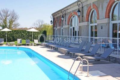 Façade d'un hôtel ancien à plusieurs étages, avec des fenêtres symétriques et un ciel bleu dégagé en arrière-plan.