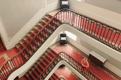 Façade d'un hôtel ancien à plusieurs étages, avec des fenêtres symétriques et un ciel bleu dégagé en arrière-plan.
