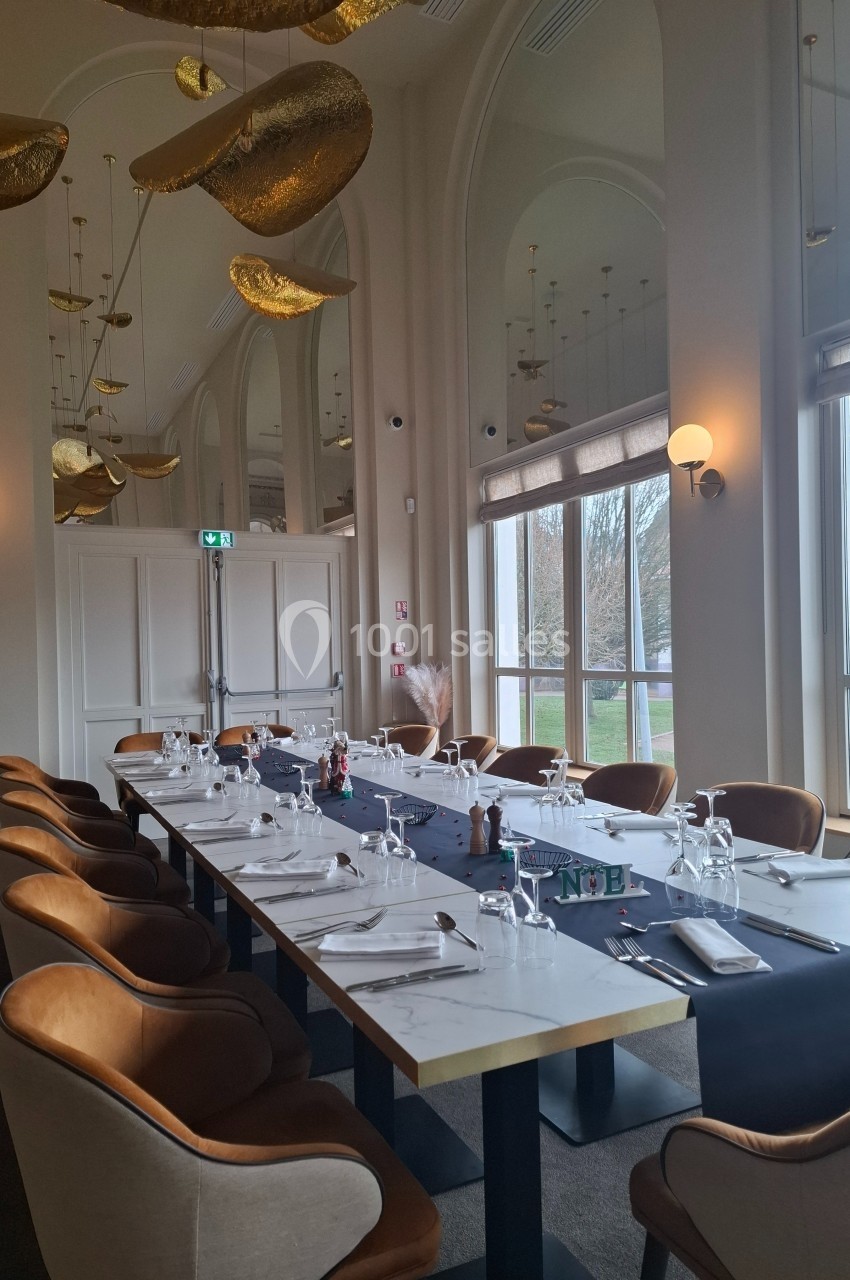Location salle Contrexéville (Vosges) - Casino Partouche de Contrexéville #18 Salle de restaurant élégante avec une grande table dressée, chaises en velours et décorations dorées suspendues.