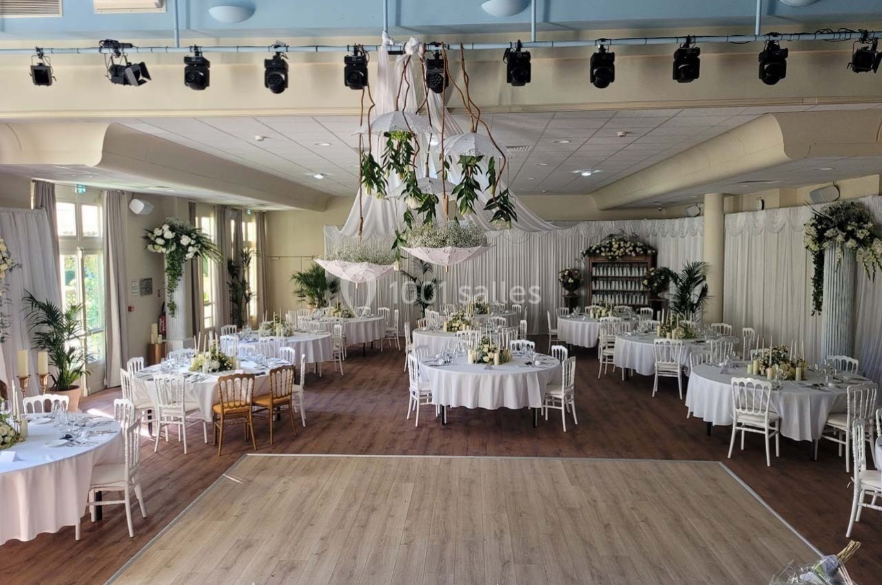 Location salle Contrexéville (Vosges) - Casino Partouche de Contrexéville #2 Salle de réception décorée pour un mariage, avec tables rondes, chaises blanches et suspensions végétales.