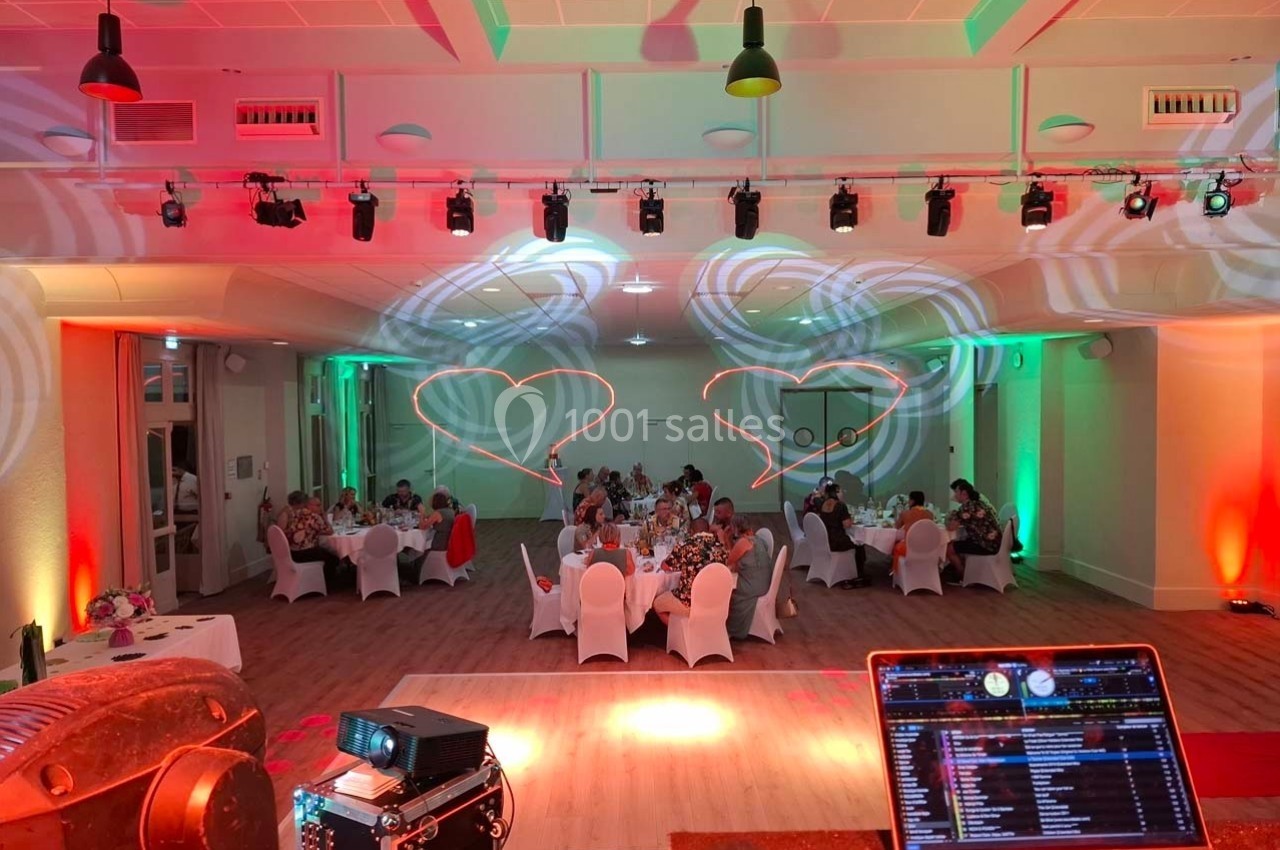 Location salle Contrexéville (Vosges) - Casino Partouche de Contrexéville #8 Salle de réception décorée avec des lumières colorées, des invités assis à des tables rondes et une console de DJ au premier…