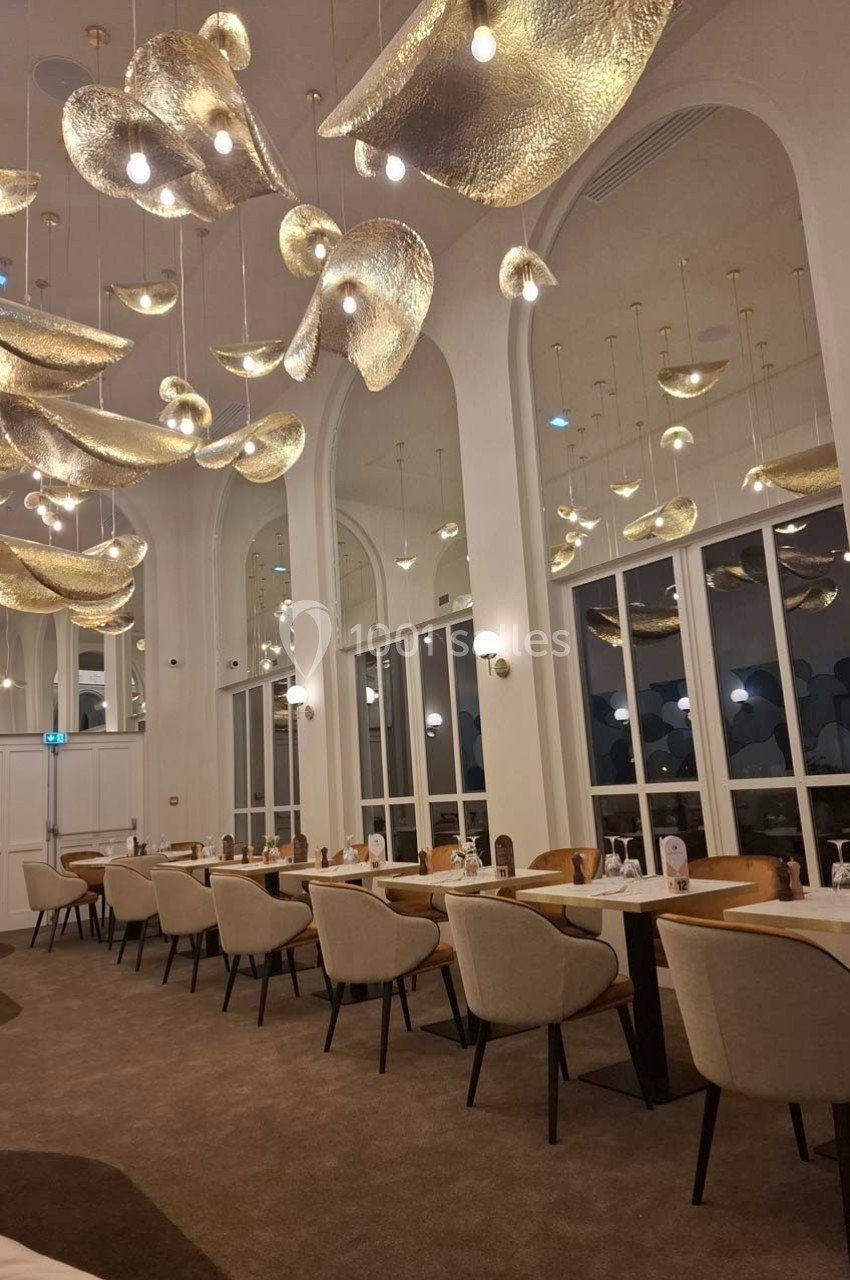 Location salle Contrexéville (Vosges) - Casino Partouche de Contrexéville #4 Salle de restaurant élégante avec des tables dressées, des chaises beige et des luminaires dorés suspendus au plafond.