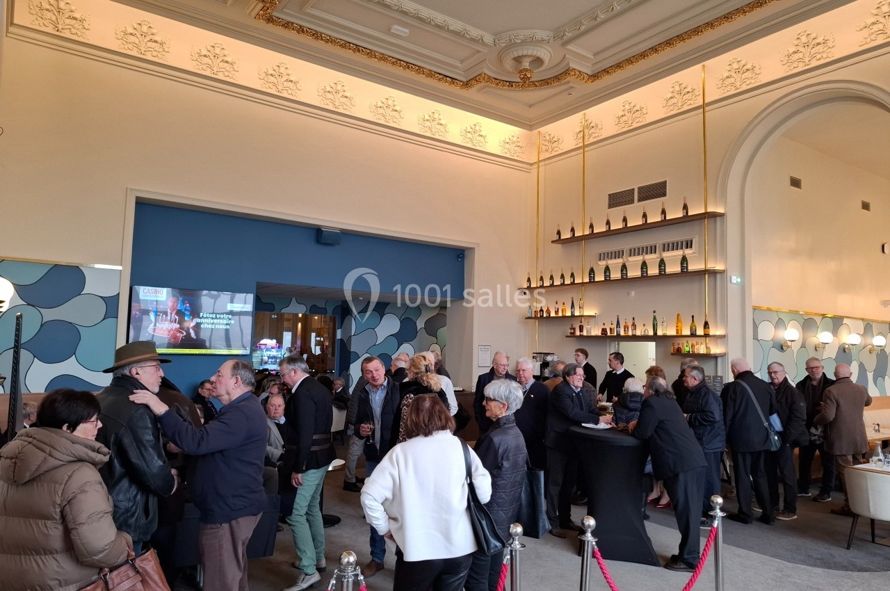 Groupe de personnes rassemblées dans un espace intérieur élégant avec un bar et une décoration lumineuse.