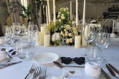 Tasse de café sur une table avec un macaron vert et un plateau de desserts flous en arrière-plan.