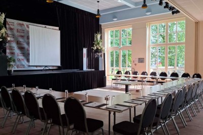 Tasse de café sur une table avec un macaron vert et un plateau de desserts flous en arrière-plan.