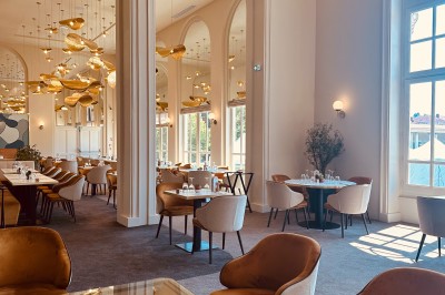 Tasse de café sur une table avec un macaron vert et un plateau de desserts flous en arrière-plan.