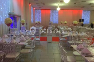 Canapé blanc orné sur une estrade rouge, entouré de colonnes dorées et de décorations florales roses.