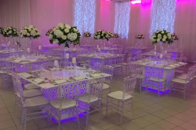 Canapé blanc orné sur une estrade rouge, entouré de colonnes dorées et de décorations florales roses.