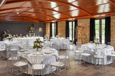 Miniature Location salle Gouvieux (Oise) - Château Jeanne & The Forest - Château de Montvillargenne #6 Un couple en tenue de mariage se tient devant une porte illuminée, entouré de briques et de végétation.