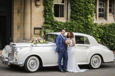 Miniature Location salle Gouvieux (Oise) - Château Jeanne & The Forest - Château de Montvillargenne #5 Un couple en tenue de mariage se tient devant une porte illuminée, entouré de briques et de végétation.