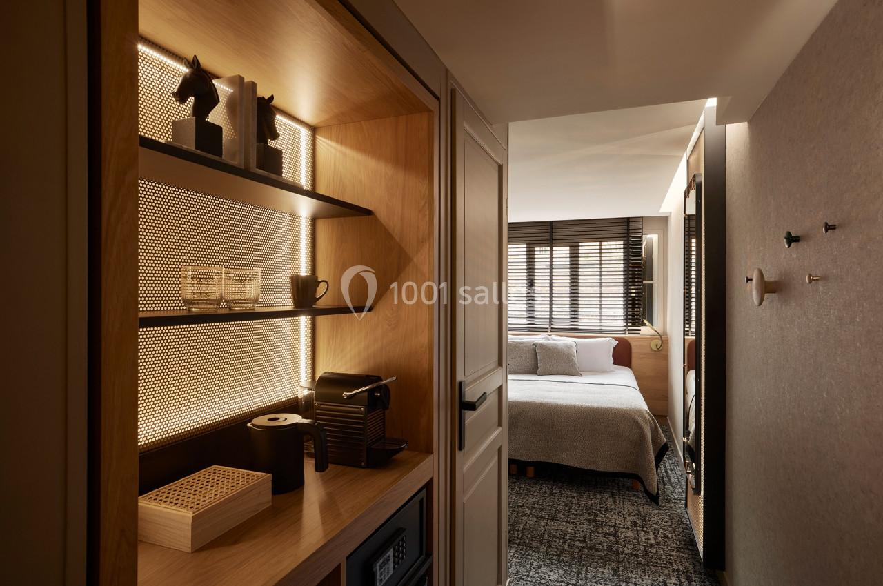 Vue d'une chambre d'hôtel avec un coin kitchenette équipé et un lit double dans un espace lumineux et moderne.