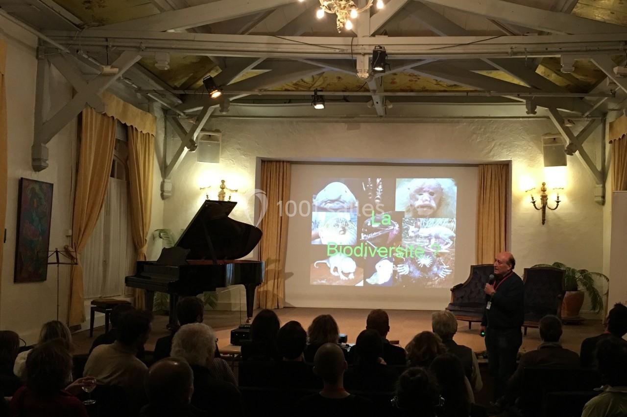 Un conférencier s'exprimant devant un public dans une salle éclairée, avec une présentation sur la biodiversité projetée.