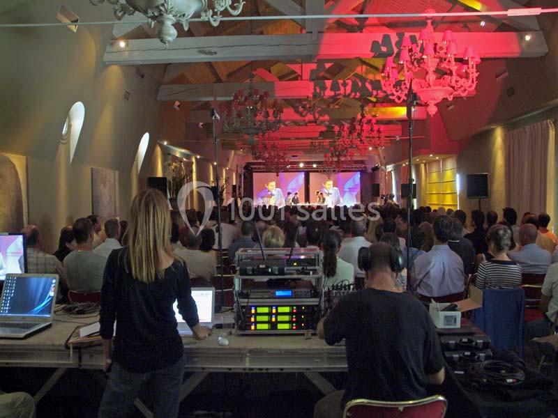 Location salle Sorgues (Vaucluse) - Château La Tour Vaucros #10 Un public assiste à un concert dans une salle éclairée, avec une régie technique visible au premier plan.