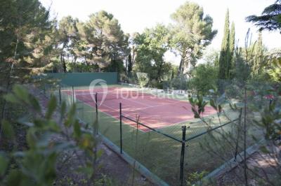 Miniature Location salle Sorgues (Vaucluse) - Château La Tour Vaucros #24 Terrain de tennis en plein air entouré de végétation et d'arbres, avec une clôture grillagée.