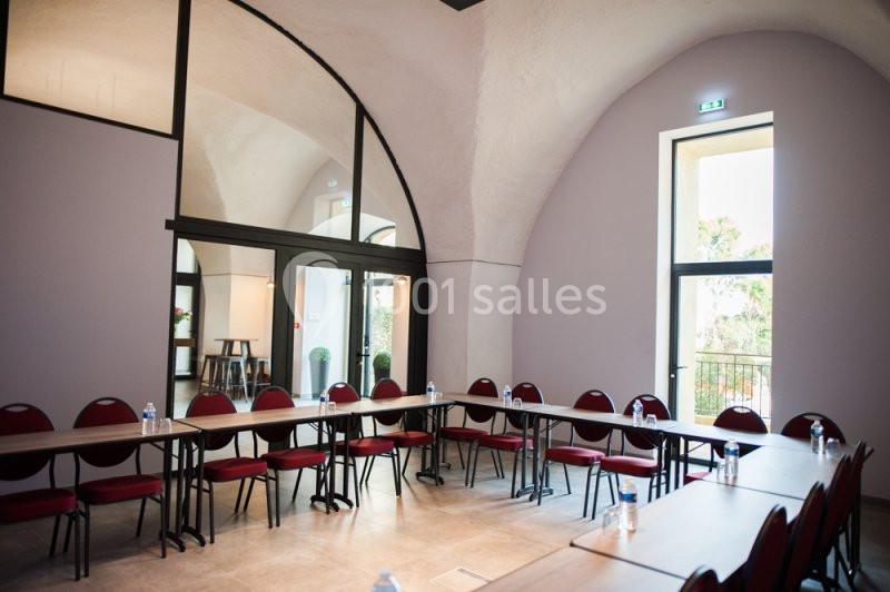 Location salle Sorgues (Vaucluse) - Château La Tour Vaucros #18 Salle de réunion lumineuse avec tables disposées en U, chaises rouges et grandes fenêtres laissant entrer la lumière…