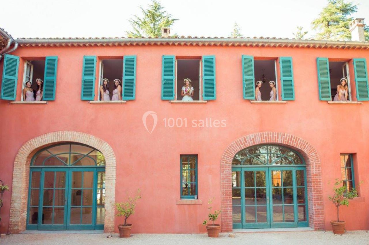 Location salle Le Cannet-des-Maures (Var) - Château Colbert Cannet #8 Façade d'une maison rose avec des volets verts, des personnes regardant par les fenêtres du premier étage.