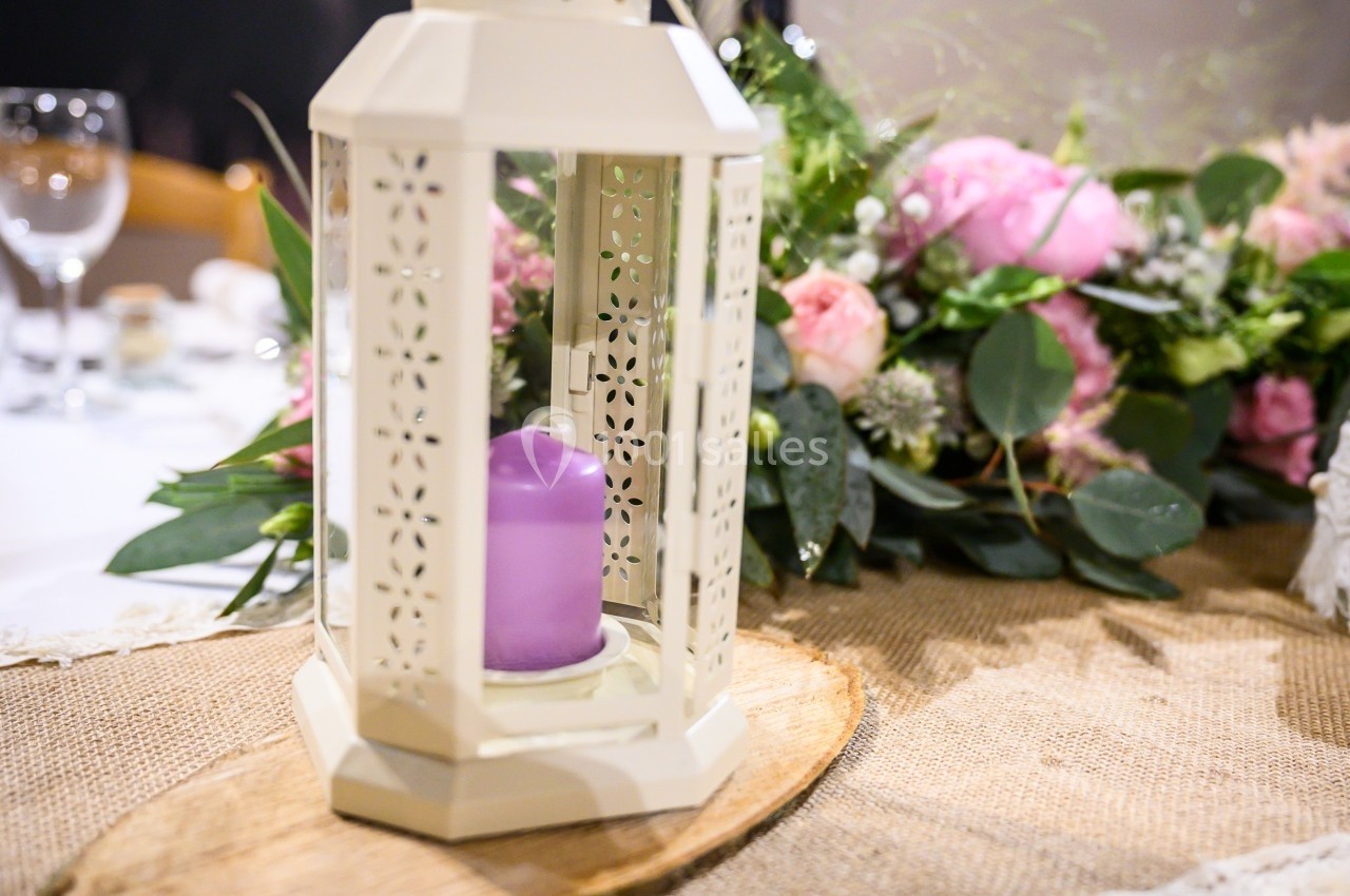 Location salle Bonneval (Eure-et-Loir) - Auberge de La Herse #2 Lanterne blanche avec bougie violette sur une table décorée de fleurs et d'un chemin de table en toile de jute.