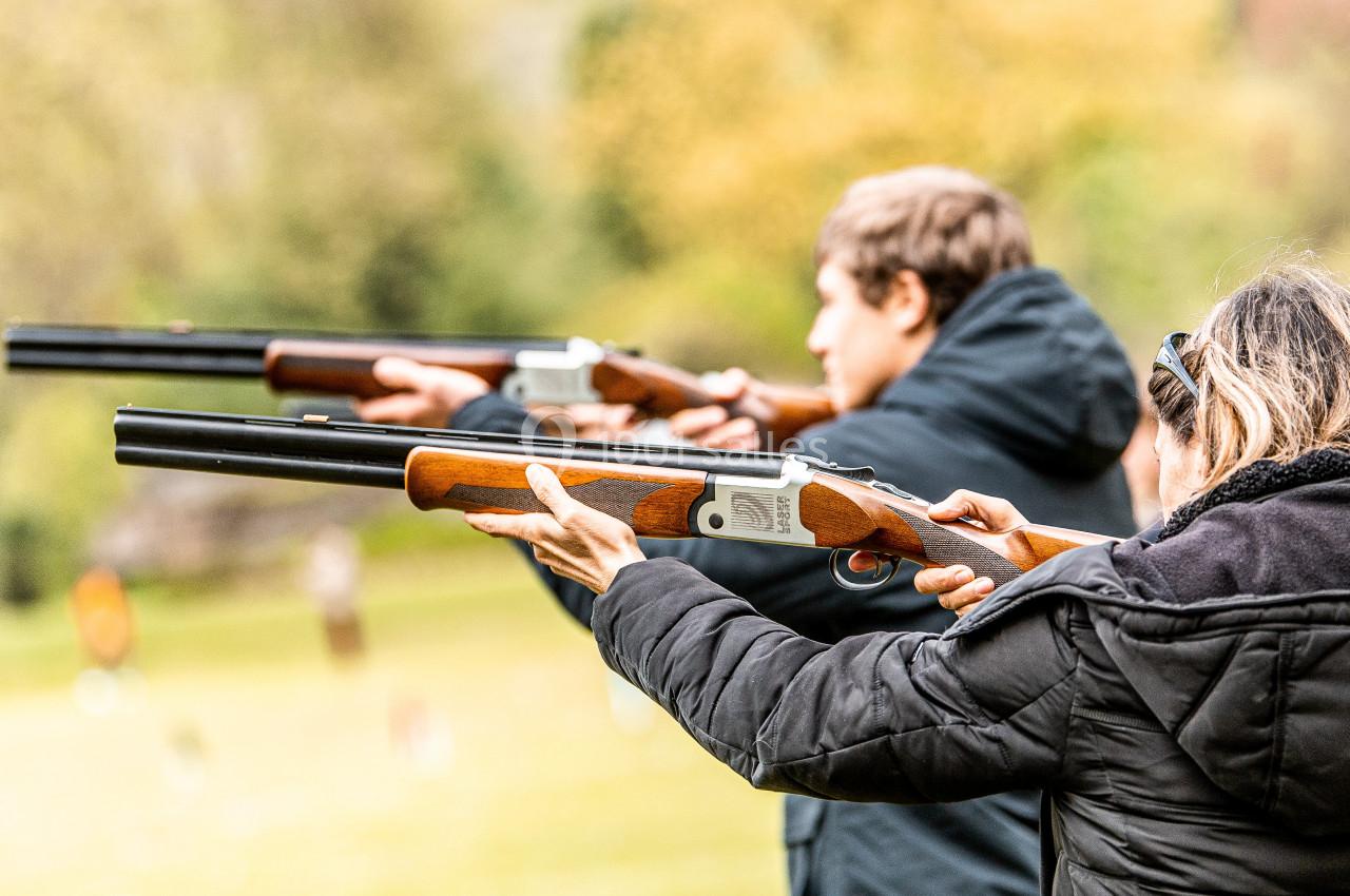 Location salle Anhée (Namur) - Ferme de l'Abbaye de Moulins #12 Personnes tenant des fusils de chasse et visant une cible en extérieur, dans un cadre naturel.