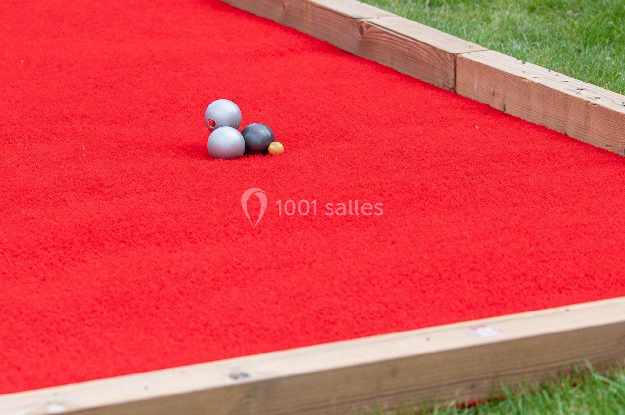 Location salle Anhée (Namur) - Ferme de l'Abbaye de Moulins #18 Terrain de pétanque avec tapis rouge, trois boules métalliques et un cochonnet posés au centre.