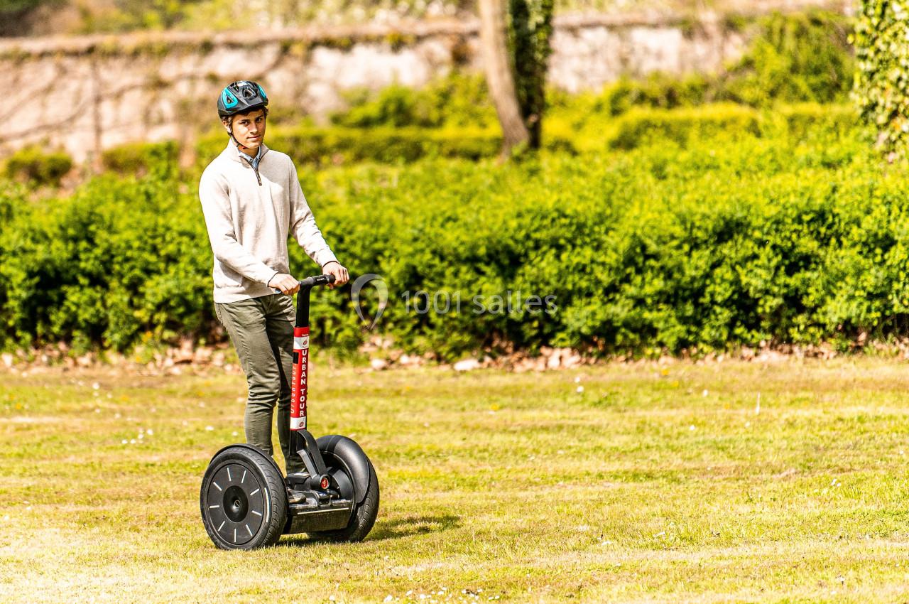 Location salle Anhée (Namur) - Ferme de l'Abbaye de Moulins #14 Un homme portant un casque roule sur un gyropode dans un parc verdoyant par une journée ensoleillée.
