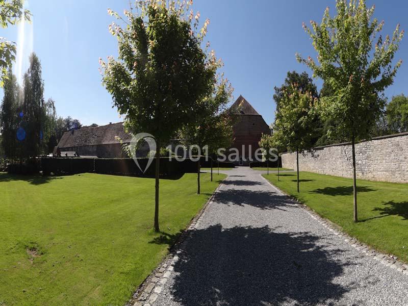 Location salle Anhée (Namur) - Ferme de l'Abbaye de Moulins #5 Allée bordée d'arbres menant à un bâtiment en briques rouges, entouré de pelouses et de murs en pierre.